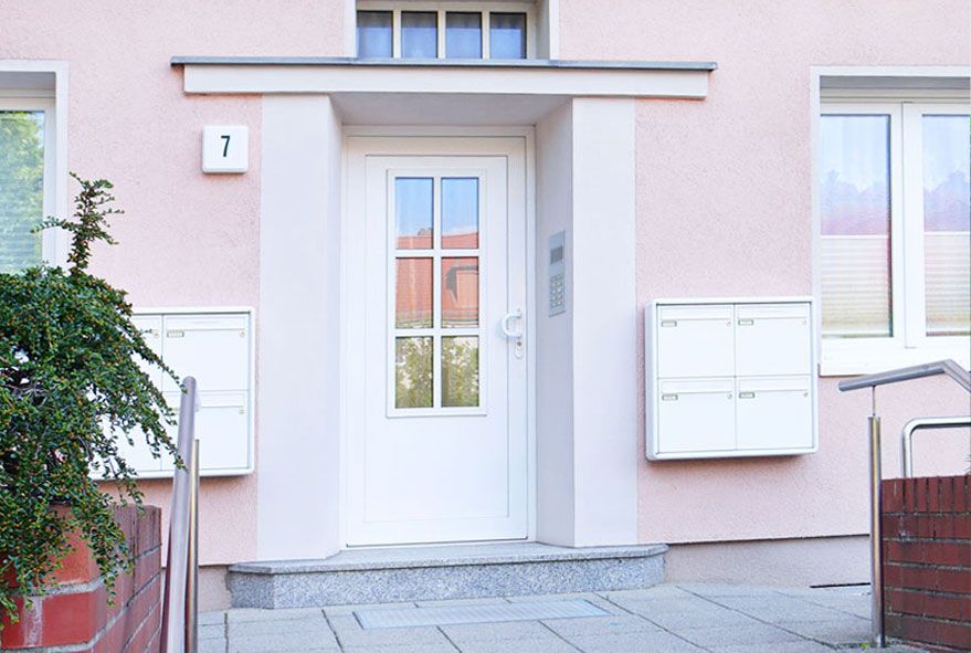 Links und rechts am Hauseingang befestigte vierer Briefkastenanlagen im Kastenformat