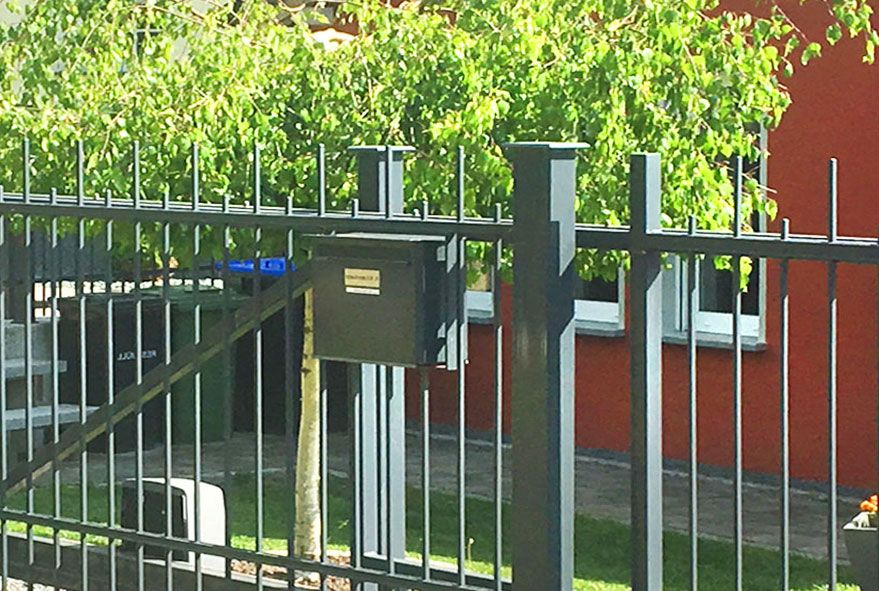 Mit bequemer Postentnahme von hinten ausgestattete Briefkästen im Zaun integriert